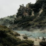 Misty geothermal landscape at Rotorua, showcasing lush vegetation and steaming waters.